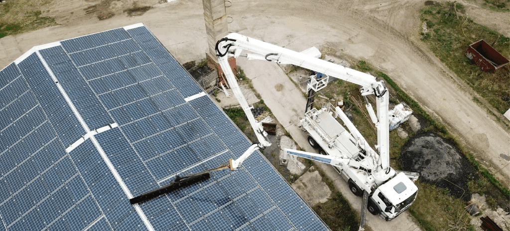 Wartung und Reinigung von Photovoltaik Anlagen auf einem Industriedach mit Hubarbeitsbühne zur Sicherstellung hoher Solarenergie-Erträge