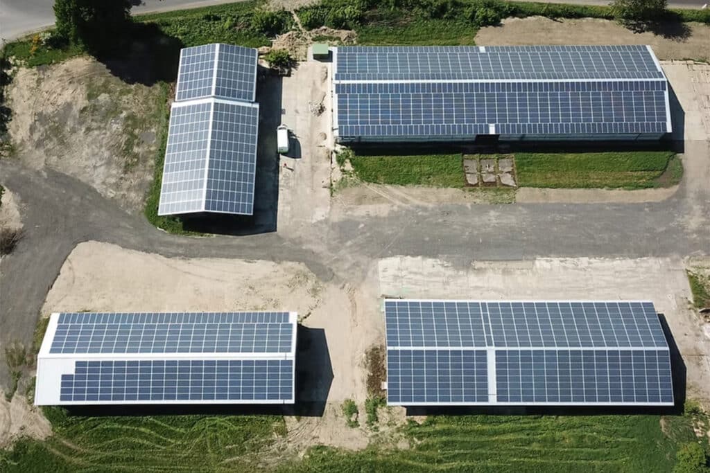 Luftaufnahme mehrerer Hallen mit großflächigen Photovoltaik-Dachanlagen, zeigt effiziente Nutzung von Dachflächen zur Solarstromerzeugung.