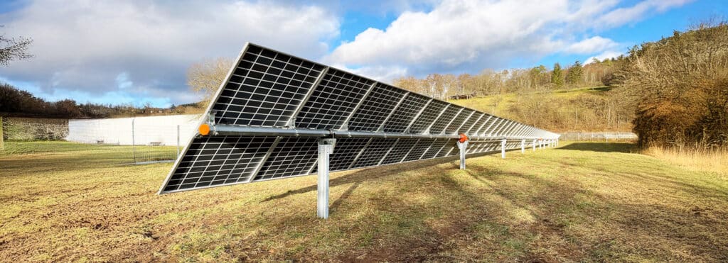Reihenweise installierte, aufgeständerte Photovoltaik-Module auf einer Grünfläche, die zur effizienten Solarstromerzeugung in einer Freiflächenanlage ausgerichtet sind.
